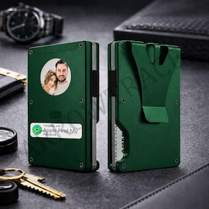 May include: Green metal wallet with a photo of a couple and a sticker that says "Works with Apple Find My network." The wallet has a money clip on the back and is shown next to a watch and keys.