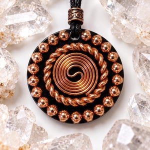 May include: A circular black pendant featuring a central copper wire spiral, surrounded by a twisted copper wire ring and an outer border of small copper beads. The pendant hangs from a black cord with a decorative copper bail.