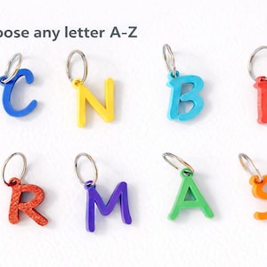 May include: A selection of brightly coloured letter keyrings in blue, yellow, turquoise, red, purple, green, and orange. Each letter has a silver keyring attached. The text "Choose any letter A-Z" is at the top.