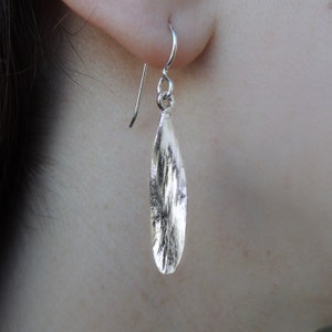 Peut inclure: Boucles d'oreilles pendantes en argent avec un pendentif en forme de feuille texturé.