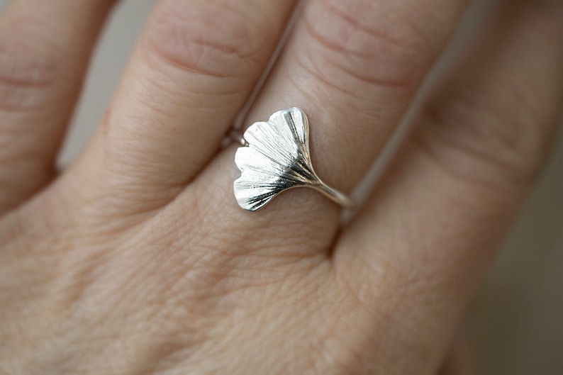 May include: A silver ring with a detailed ginkgo leaf design.