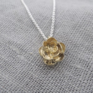 May include: A gold rose pendant necklace on a silver chain. The rose is a detailed, textured design.