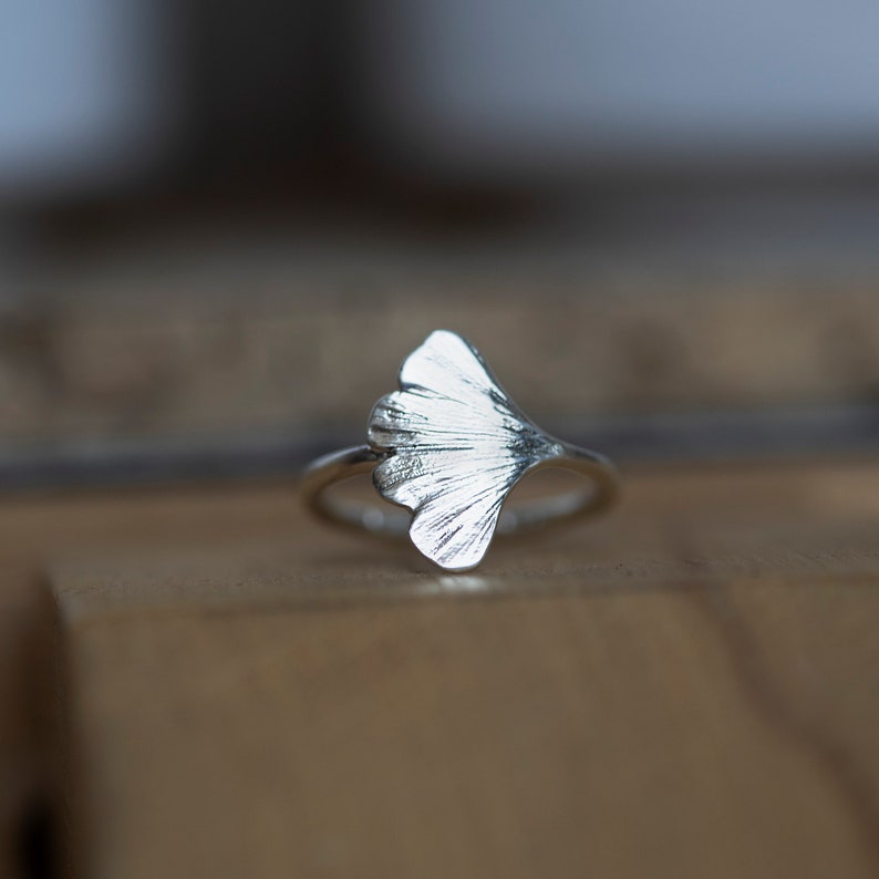 May include: A silver ring with a ginkgo leaf design. The leaf is detailed and textured.