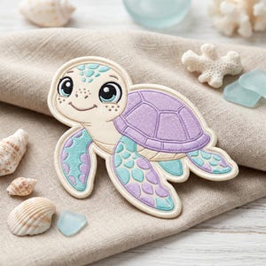 May include: An embroidered patch shaped like a sea turtle with a cream-colored head and body, a lavender shell, and flippers featuring a pattern of light blue and lavender scales. The turtle has large black eyes and a small smiling mouth.