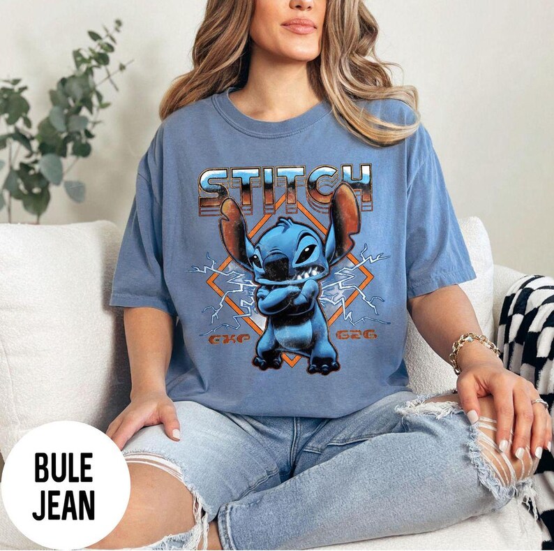 Puede incluir: Camiseta azul claro con un gr&aacute;fico del personaje Stitch de Lilo & Stitch. La palabra "STITCH" est&aacute; impresa encima del personaje, con rayos y las letras "GKP" y "G2G" debajo. La camiseta es de color azul claro.