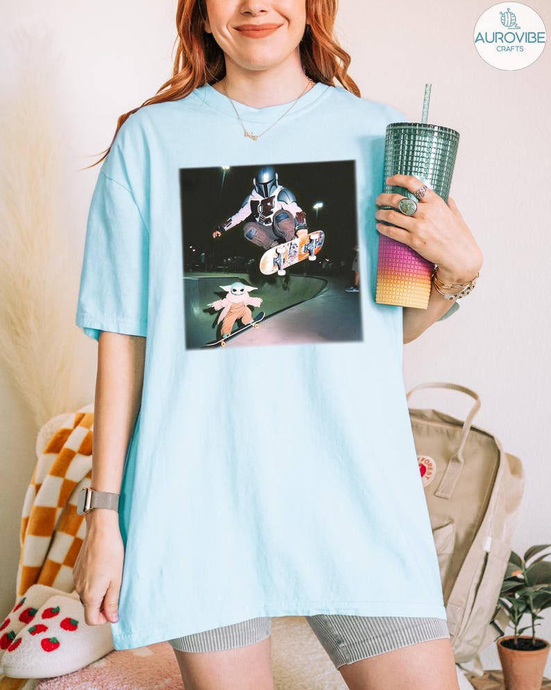 Puede incluir: Camiseta azul claro con un estampado gr&aacute;fico de un skater y un personaje peque&ntilde;o. El gr&aacute;fico est&aacute; sobre un fondo oscuro. La camiseta es de color azul claro.