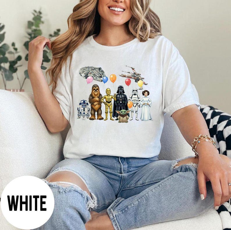 Peut inclure: T-shirt blanc avec un motif color&eacute; de personnages de Star Wars, dont R2-D2, Chewbacca, C-3PO, Dark Vador, un Stormtrooper, la Princesse Leia et Baby Yoda. Le motif comprend des ballons et des vaisseaux spatiaux.