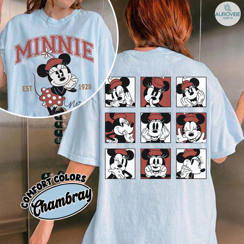 May include: Light blue t-shirt featuring a Minnie Mouse graphic. The front displays "MINNIE" in red lettering with a Minnie Mouse illustration and the text "EST 1928". The back has a grid of Minnie Mouse images. The shirt is made of Comfort Colors Chambray fabric.