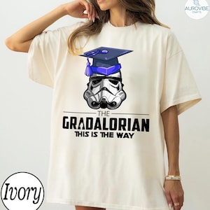 Pu&ograve; includere: T-shirt color avorio con grafica di un casco da Stormtrooper con cappello di laurea. Il testo "THE GRADALORIAN THIS IS THE WAY" &egrave; stampato in nero. La maglietta ha una vestibilit&agrave; ampia.