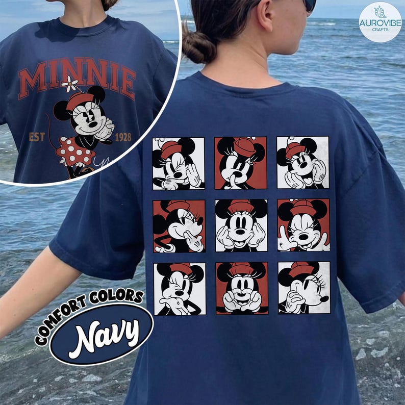 May include: Navy blue t-shirt featuring Minnie Mouse graphics. The front displays "MINNIE" with a vintage design and the year "1928". The back showcases a grid of Minnie Mouse expressions. The shirt has a "COMFORT COLORS" label.