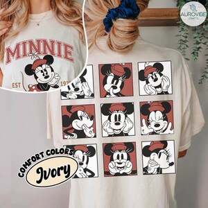 May include: Ivory-colored t-shirt featuring a Minnie Mouse design. The front displays "MINNIE" in red lettering with a Minnie Mouse graphic. The back showcases nine Minnie Mouse illustrations in red squares. The shirt also has the text "COMFORT COLORS" and "Ivory".