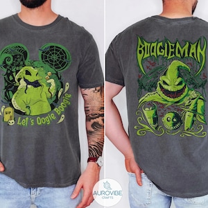 May include: A charcoal grey t-shirt featuring a green graphic of Oogie Boogie on the front with the text Let's Oogie Boogie and a larger green graphic on the back with the text BOOGIEMAN, showcasing a spooky character design with spiderwebs.