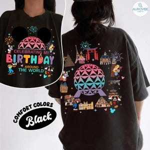 Op de afbeelding: Zwart T-shirt met een kleurrijk grafisch ontwerp. De voorkant heeft een Mickey Mouse-hoofdvorm met een geometrisch ontwerp en de tekst "Celebrating My Birthday Around The World". De achterkant heeft verschillende bezienswaardigheden en personages.