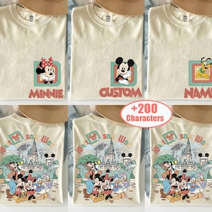 May include: Cream-colored t-shirts with Disney character designs. One shirt features Minnie Mouse, another Mickey Mouse, and a third Pluto. The bottom row of shirts displays a Walt Disney World graphic with various characters.