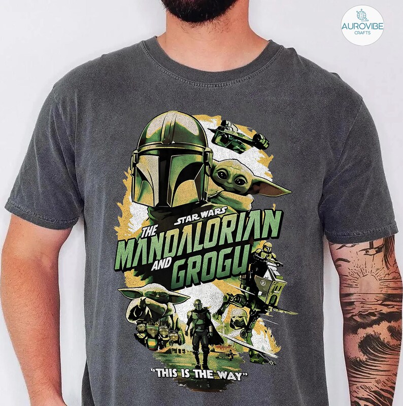 Pode incluir: Camiseta cinza escuro com um design gr&aacute;fico da s&eacute;rie Star Wars, "The Mandalorian and Grogu". O design inclui o capacete Mandaloriano, Grogu e o texto "THIS IS THE WAY."