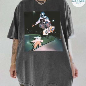 Puede incluir: Camiseta gris oscuro con un gr&aacute;fico de The Mandalorian y Grogu patinando en un skate park. El Mandaloriano est&aacute; en el aire, haciendo un truco en su patineta. Grogu est&aacute; montando su patineta en la rampa. La camiseta tiene un corte holgado.