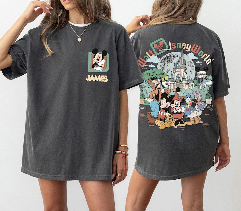 May include: Dark gray t-shirt featuring Mickey Mouse on the front and a Walt Disney World graphic on the back. The front design includes Mickey Mouse in a square frame with the name "JAMES" below. The back design shows Disney characters and a castle.
