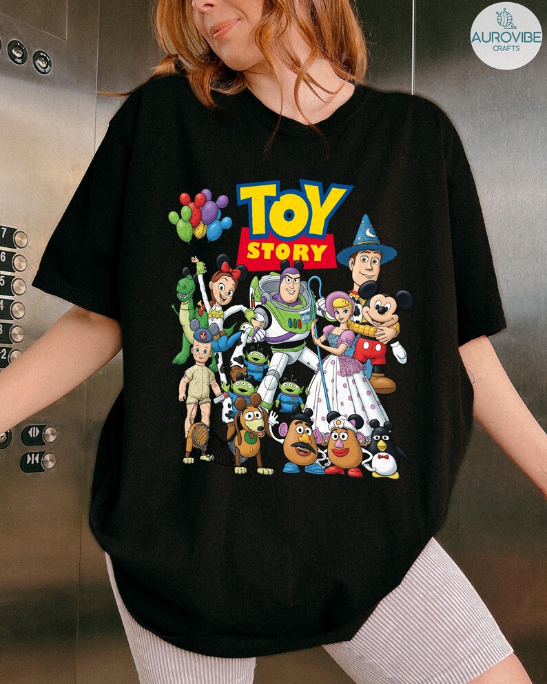 Op de afbeelding: Zwart T-shirt met het "Toy Story" logo en een kleurrijke afbeelding van personages uit de animatiefilm. Het ontwerp bevat Buzz Lightyear, Woody en andere geliefde personages. Een leuk en levendig ontwerp voor fans van de film.