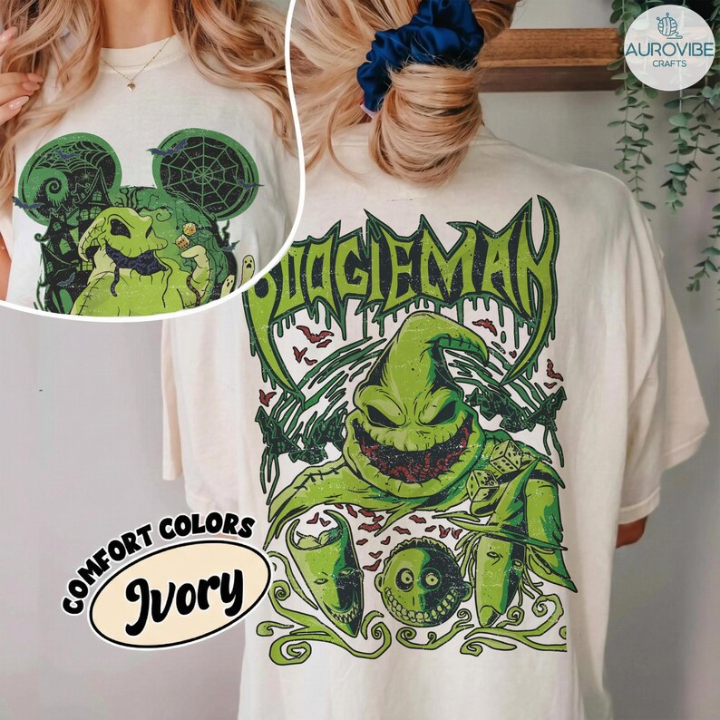 May include: An ivory t-shirt featuring a large graphic print on the back of a green, sack-like character with a wide, toothy grin, dice, and the text BOOGIEMAN in a dripping font. A smaller version of the graphic is printed on the front chest area.
