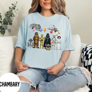 Peut inclure: T-shirt bleu clair avec des personnages et des vaisseaux spatiaux Star Wars et des ballons color&eacute;s. Le design comprend R2-D2, Chewbacca, C-3PO, Dark Vador, un Stormtrooper, la Princesse Leia et Baby Yoda.