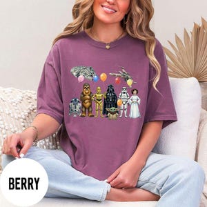 Peut inclure: T-shirt de couleur baie avec un motif Star Wars. Le design comprend des personnages tels que R2-D2, Chewbacca, C-3PO, Dark Vador, un Stormtrooper et la Princesse Leia. Des ballons et des vaisseaux spatiaux compl&egrave;tent l'illustration.