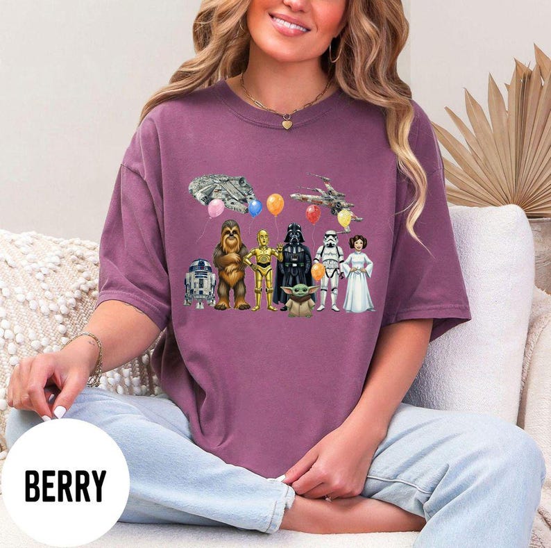 Peut inclure: T-shirt de couleur baie avec un motif Star Wars. Le design comprend des personnages tels que R2-D2, Chewbacca, C-3PO, Dark Vador, un Stormtrooper et la Princesse Leia. Des ballons et des vaisseaux spatiaux compl&egrave;tent l'illustration.