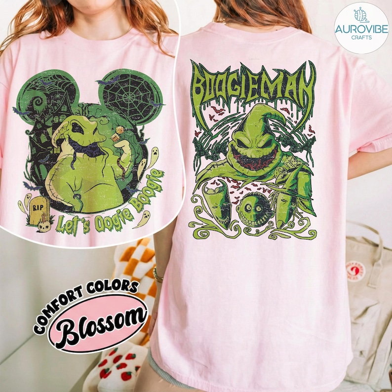 May include: A light pink t-shirt featuring a graphic of a green burlap sack character with a wide grin. The back design displays the text BOOGIEMAN in a stylised font above the character, while the front design shows the character with the text Let's Oogie Boogie and a tombstone marked RIP.