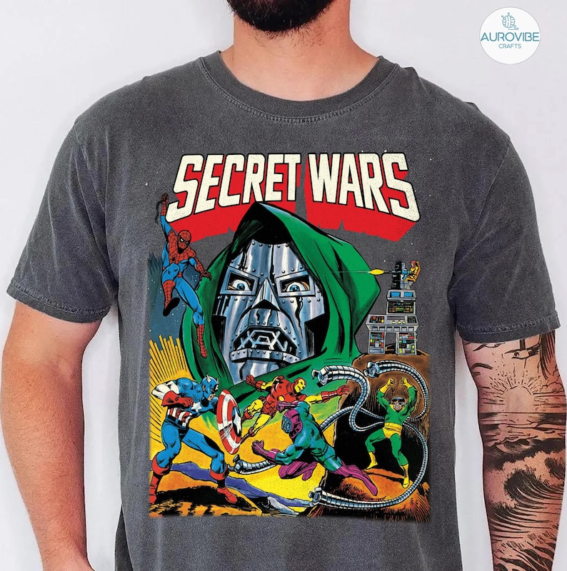 May include: Dark gray t-shirt featuring a comic book illustration with the text "SECRET WARS." The graphic depicts Spider-Man, Captain America, Iron Man, and Doctor Doom in a battle scene. The shirt has a vintage, distressed look.