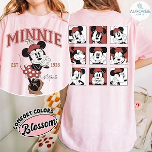 May include: Pink t-shirt featuring Minnie Mouse. The front displays a graphic of Minnie with the word "MINNIE" in maroon, "EST 1928", and "Minnie" in script. The back has nine square images of Minnie Mouse. The shirt has the text "COMFORT COLORS Blossom".
