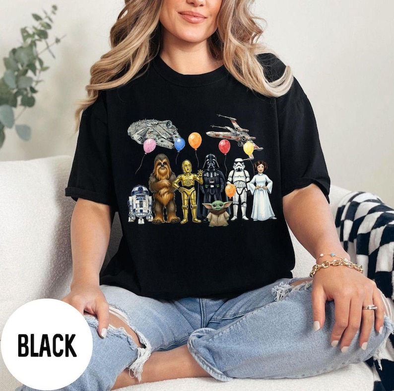 Peut inclure: T-shirt noir avec un motif Star Wars. Le motif comprend des illustrations de personnages tels que R2-D2, Chewbacca, C-3PO, Dark Vador, un Stormtrooper et la Princesse Leia, ainsi qu'un Faucon Millenium et un X-wing.
