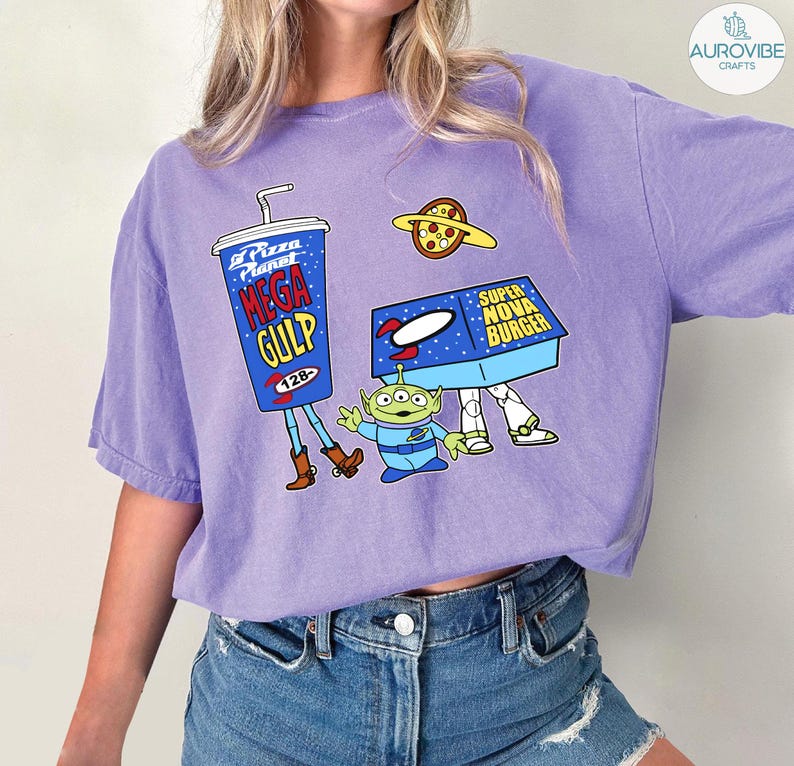 以下が含まれることがあります： 人気アニメ映画の漫画グラフィックが特徴のライラック色のTシャツ。デザインには、メガガルのカップ、ピザプラネット、スーパーノヴァバーガーボックス、緑色のエイリアンキャラクターが含まれています。このシャツは快適でカジュアルなスタイルです。