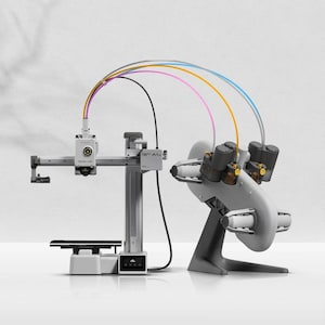 May include: A modern, gray and white 3D printer with multiple nozzles and colorful tubes. The printer has a rectangular base and a robotic arm. The image is well-lit, showcasing the printer's design and components.