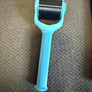 May include: A light blue roller with a black cylindrical roller head. The handle is ribbed for grip. The roller is designed for a specific purpose, likely for applying a substance or smoothing a surface.
