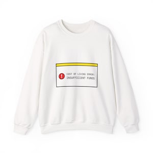 May include: White crew neck sweatshirt. The front displays a graphic of a computer error message: "COST OF LIVING ERROR: INSUFFICIENT FUNDS" in black text, with a red exclamation mark.