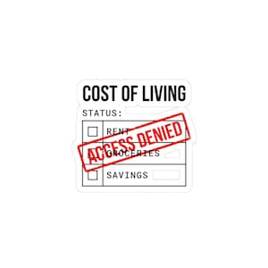 May include: A white sticker with the words "COST OF LIVING" in black, above a checklist. The checklist includes "RENT", "GROCERIES", and "SAVINGS". A red stamp reads "ACCESS DENIED" across the checklist.
