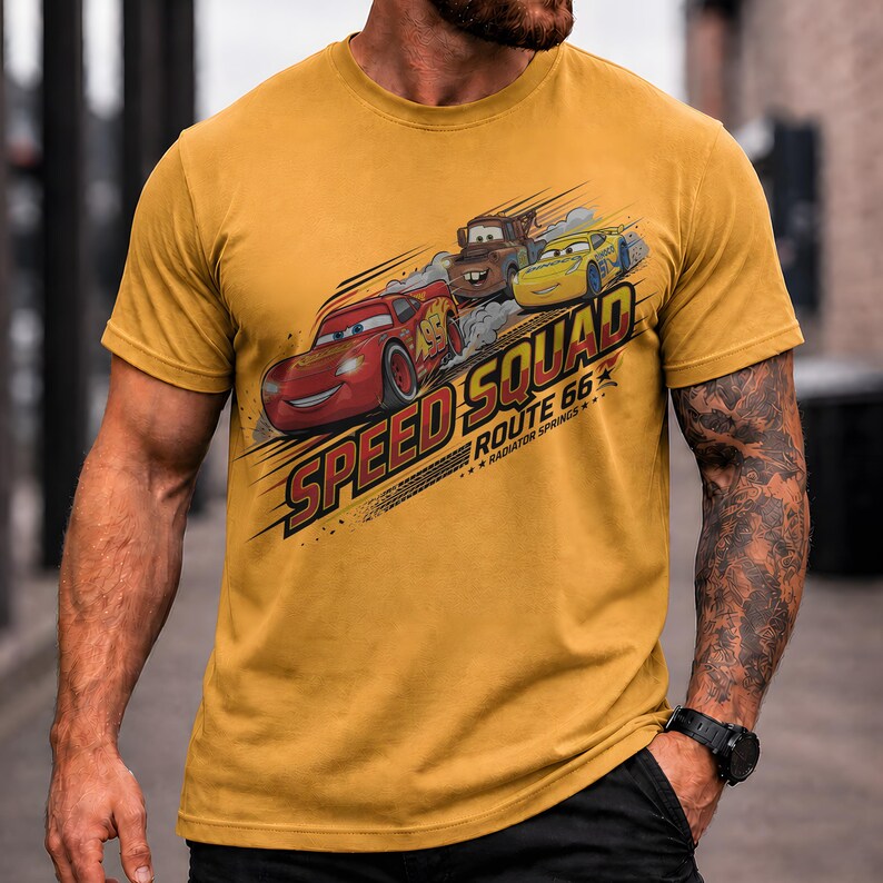 Op de afbeelding: Mosterdgeel T-shirt met een afbeelding van drie cartoon raceauto's en de tekst "Speed Squad Route 66 Radiator Springs". Het ontwerp bevat een rode auto, een bruine auto en een gele auto.