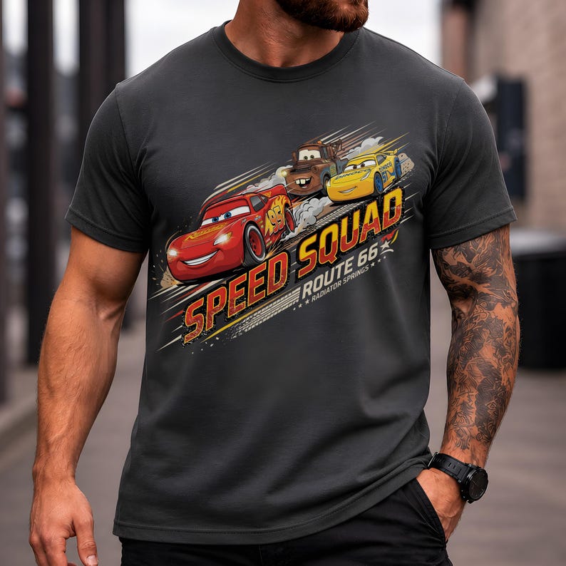 Op de afbeelding: Donkergrijs t-shirt met de tekst "SPEED SQUAD ROUTE 66 RADIATOR SPRINGS" en illustraties van Bliksem McQueen, Takel en een gele auto. Het ontwerp heeft een racethema.
