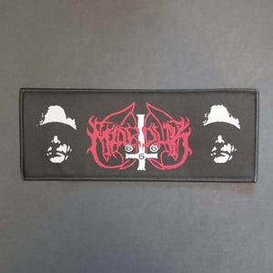 Peut inclure: Écusson rectangulaire noir avec un motif rouge et blanc. Le motif comprend une croix inversée stylisée avec le chiffre 6 de chaque côté et deux silhouettes de visage blanches. Le mot "MORBID" est écrit en rouge.