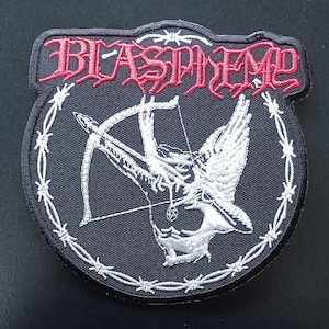 May include: A black embroidered patch featuring the word BLASPHEMY in red gothic lettering at the top. The centre displays a white winged figure holding a bow and arrow, encircled by a white barbed wire border on a black fabric background.