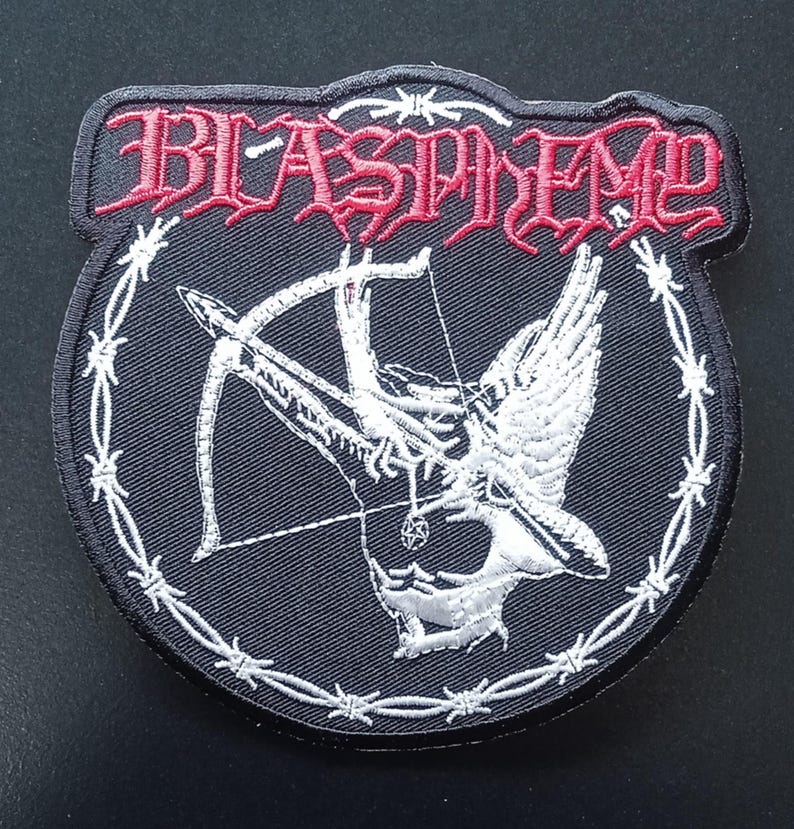 May include: A black embroidered patch featuring the word BLASPHEMY in red gothic lettering at the top. The center displays a white winged figure holding a bow and arrow, encircled by a white barbed wire border on a black fabric background.