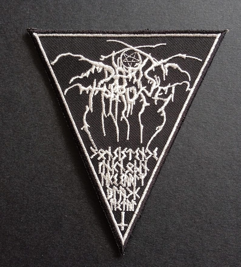 Puede incluir: Un parche triangular negro bordado con detalles en hilo blanco. El dise&ntilde;o incluye el texto Darkthrone en una fuente estilizada, un pentagrama, texto adicional ilegible y una cruz invertida en la punta inferior del tri&aacute;ngulo.