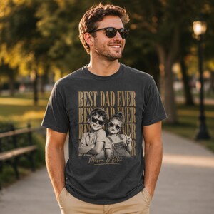 May include: Dark gray t-shirt with the text "BEST DAD EVER" in a stacked design. Below the text is a sepia-toned photo of two children wearing sunglasses. The names "Mason & Ellie" are printed below the photo.