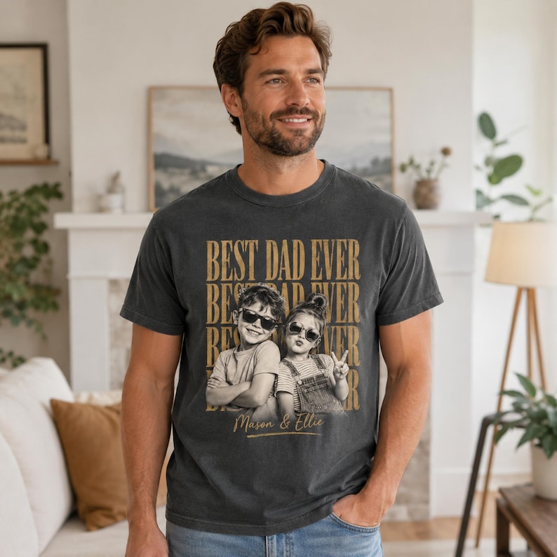 May include: Dark gray t-shirt with the text "BEST DAD EVER" in gold lettering. The shirt features a sepia-toned photo of two children wearing sunglasses. The children's names, Mason & Ellie, are printed below the photo.