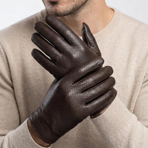 May include: Dark brown leather gloves with a perforated design. The gloves are made of a soft, supple leather and have a classic, timeless style. The gloves are designed to provide warmth and protection.