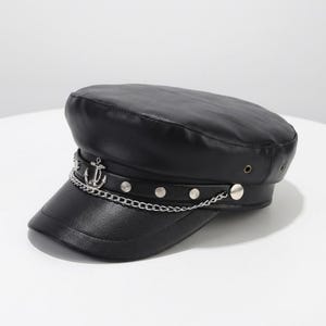Pode incluir: Chapéu de marinheiro preto com corrente prateada e detalhe de âncora. O chapéu tem uma coroa arredondada e uma aba curta e plana. A corrente é presa à aba com pequenos pregos prateados. O chapéu é feito de um material liso semelhante ao couro.