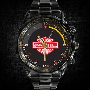 May include: Black wristwatch with a black band and face. The watch face features a red and white logo with the text "BIG RED SUPPORT UR LOCAL MACHINE". Gold-colored hands and accents complete the design.