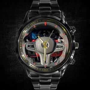 Può includere: Orologio da polso nero con quadrante trasparente che mostra un volante e un cruscotto di un'auto. L'orologio ha un cinturino in metallo nero e un quadrante centrale dorato. Il quadrante mostra numeri e dettagli rossi.