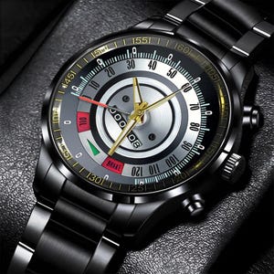 May include: A black wristwatch with a metallic band and a detailed face. The watch face features a silver and black design with gold accents, including hands and markers. The watch has a date display and various gauges.