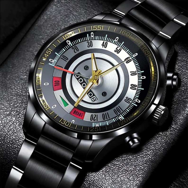 May include: A black wristwatch with a metallic band and a detailed face. The watch face features a silver and black design with gold accents, including hands and markers. The watch has a date display and various gauges.
