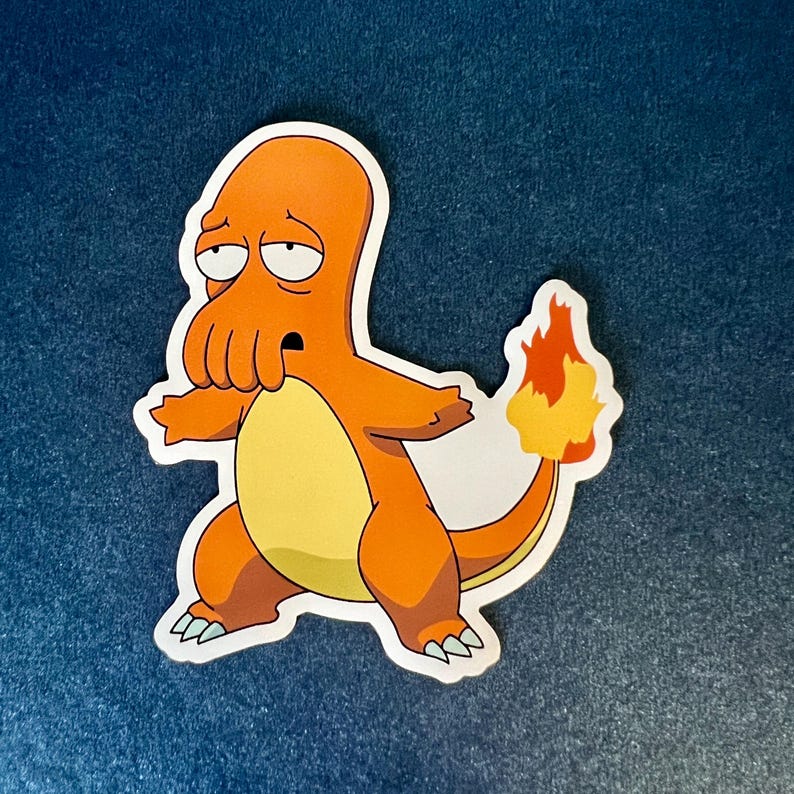 Op de afbeelding: Een gestanste sticker met een oranje stripfiguur met een gele buik en een vlamstaart. Het personage heeft een trieste uitdrukking. De sticker is ontworpen om op verschillende oppervlakken te worden aangebracht.